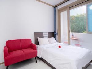 a bedroom with a red chair and a bed at Samcheo Happy House Pension in Samcheok