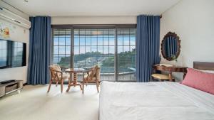 une chambre avec un lit, une table et un bureau dans l'établissement Ganghwado Happyvilly Pension, à Incheon