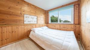 1 dormitorio con 1 cama en una habitación con paneles de madera en boryeong hiddenvillage dokchae poolvilla, en Boryeong