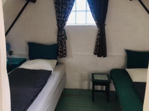 two beds in a small room with a window at Unique place on the river Waal in Heerewaarden