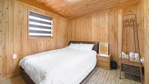 a bedroom with a bed in a wooden room at jeju bijalim pension in Jeju +1 photo
