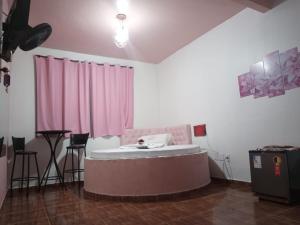 una camera con un letto in una stanza con tende rosa di Hotel canal hum samambaia a Brasilia Altre 3 foto