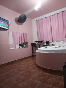 una stanza con tende rosa, un tavolo e delle sedie di Hotel canal hum samambaia a Brasilia