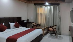 a bedroom with a bed and a desk and a window at Hotel Ram Janaki Palace in Tikri Kalān +12 photos
