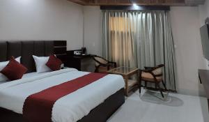 a hotel room with a bed and a desk and a window at Hotel Ram Janaki Palace in Tikri Kalān