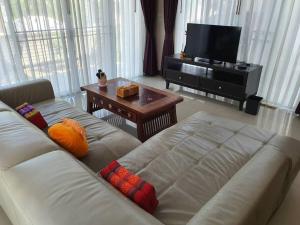 ein Wohnzimmer mit einem weißen Sofa und einem Fernseher in der Unterkunft Modern private home in quiet gated community in Ban Hua Khao Sammuk