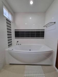 eine weiße Badewanne in einem Badezimmer mit Fenster in der Unterkunft Modern private home in quiet gated community in Ban Hua Khao Sammuk