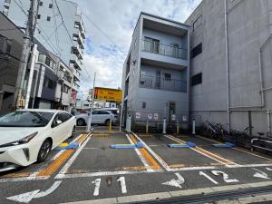 a white car parked in a parking lot next to a building at The Peak Tengachaya in Osaka