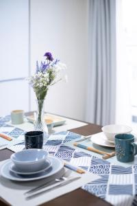 a table with plates and cups and a vase of flowers at The Peak Tengachaya in Osaka