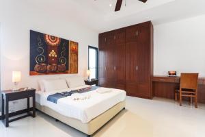 ein Schlafzimmer mit einem Bett und einem Gemälde an der Wand in der Unterkunft Frangipani pool villa - garden, BBQ & maid in Nai Harn Beach + 39 Fotos