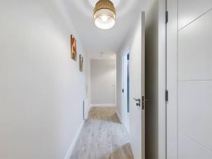 a hallway with white walls and a light fixture at Trendy 2-Bedroom Belfast Apartment in Belfast +3 photos