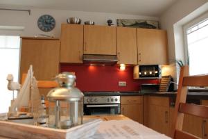 a kitchen with wooden cabinets and a stove top oven at Das GrachtenDOMiZiL Greetsiel in Greetsiel