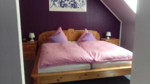 Schlafzimmer mit einem Bett mit rosa Bettwäsche und Kissen in der Unterkunft Hotel am Schenkelberg in Saarbrücken