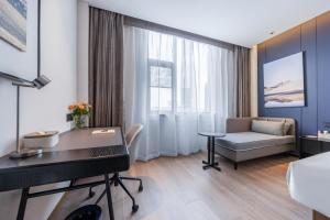 a room with a desk and a couch and a table at Atour Hotel Maitreya Avenue Huquan Ecological Park in Mile