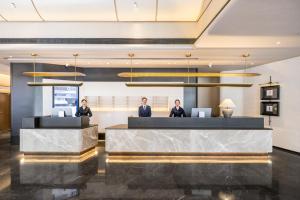 a lobby with three people sitting at a reception desk at Atour Hotel Maitreya Avenue Huquan Ecological Park in Mile