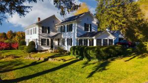 a white house on a green yard with a tree at Whitney by AvantStay Private Berkshires Estate in Sheffield