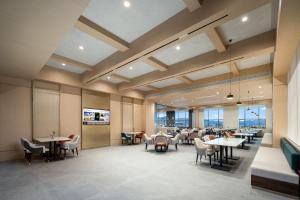 une salle à manger avec tables, chaises et fenêtres dans l'établissement Atour Hotel Tengchong Wenxing Building, à Tengchong