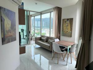 una sala de estar con un sofá y una mesa en Apartment with panoramic views at Oceana by Lofty, en Kamala Beach