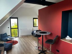 a room with a red wall and a table and chairs at Ty Nid d'Amour Ty Matlo in Névez