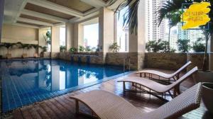 a swimming pool in a hotel with chairs and tables at KL Rooms at Greenbelt makati with cityview in Manila