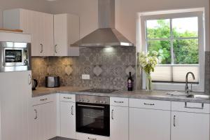 a kitchen with white cabinets and a stove top oven at Reethaus 1A in Staberdorf