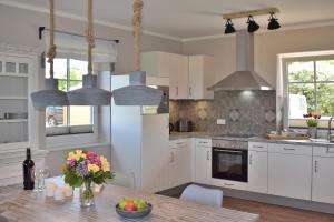 a kitchen with white cabinets and a wooden table at Reethaus 3A in Staberdorf