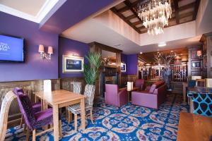 un restaurante con paredes moradas, mesas y sillas en The White Lady Wetherspoon, en Edimburgo