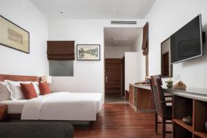 a bedroom with a bed and a desk and a television at Lynnaya Urban River Resort in Siem Reap