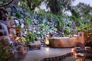 a stone wall with a fountain and some plants at Lynnaya Urban River Resort in Siem Reap