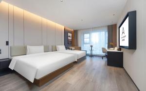 a bedroom with a large white bed and a flat screen tv at Atour Hotel Kunming Tongde Plaza Beijing Road in Kunming