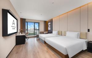 a hotel room with two beds and a flat screen tv at Atour Hotel Kunming Tongde Plaza Beijing Road in Kunming