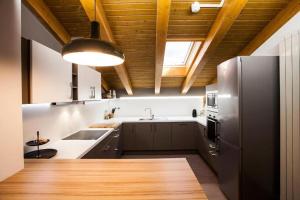 a kitchen with a stainless steel refrigerator and wooden ceilings at La Xiquella, formatges artesans i masoveria in Bas