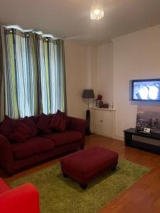 Una sala de estar con un sofá rojo y un televisor de pantalla plana. en Comfy 1 bed Workers Apartment, en Aberdeen