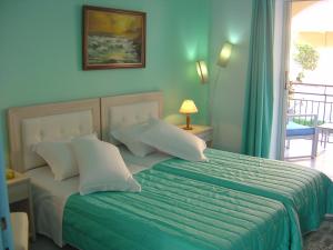 a bedroom with a bed with a green comforter at Roda Pearl Resort in Roda