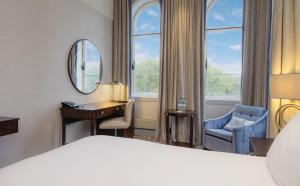 a hotel room with a bed and a desk and a mirror at Glasgow Grosvenor Hotel in Glasgow