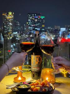 胡志明市Happy Life Grand Hotel & Rooftop Skybar的两人在桌子上拿着酒杯