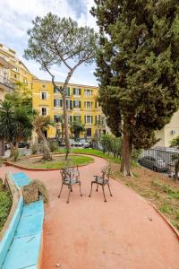 park z dwoma ławkami i żółtym budynkiem w obiekcie CRISPI 74.1 - Apartment w mieście Neapol