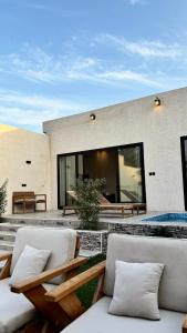 a patio with two white chairs and a building at شاليهات بالما in Al Hofuf