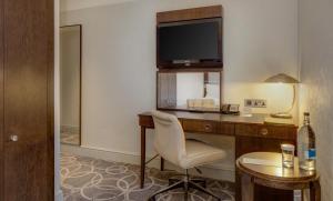 a hotel room with a desk with a television and a chair at Glasgow Grosvenor Hotel in Glasgow