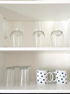 une rangée de verres et de tasses sur des étagères dans l'établissement Grand Central House - Central Penthouse Two Bedroom - GibraltarStay Apartments, à Gibraltar