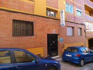 a blue car parked in front of a brick building at Pensión Aries II in Cuenca