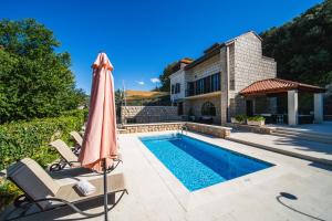 an umbrella and chairs next to a swimming pool at Villa Franica in Dubrovnik