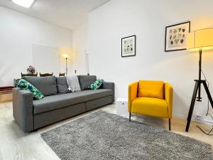a living room with a gray couch and a yellow chair at 2 Zimmer Apartment für 6 P, 15 min zum Flughafen in Sirnau