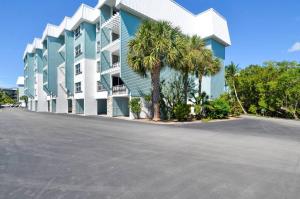 a large building with palm trees in front of it at Dune Wind South by AvantStay Communal Pool Hot Tub Gated Community Close to Smathers Beach Month Long Stays Only in Key West