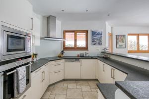 a large kitchen with white cabinets and a tv at Lodge 3 Nordic Bath & Garden in Champéry