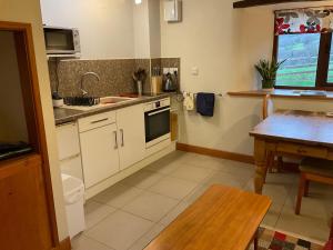 a kitchen with white cabinets and a wooden table at Lind End Cottage in Broughton in Furness