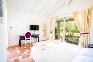 ein Schlafzimmer mit einem großen weißen Bett und einem Schreibtisch in der Unterkunft Nicolaus Prime Villas Resort in Costa Rei + 45 Fotos