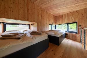 two beds in a room with wooden walls at Treeangle - K1 Baumhaus in Odenthal