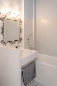 een witte badkamer met een wastafel en een spiegel bij Logis Le Pont Bernet in Le Pian-Médoc