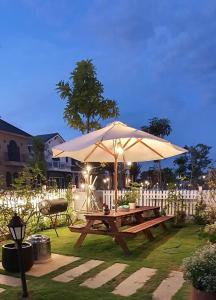 a picnic table with an umbrella in a yard at Novaworld Phan Thiết - Luxury villa 4 Phòng Ngủ in Phan Thiet